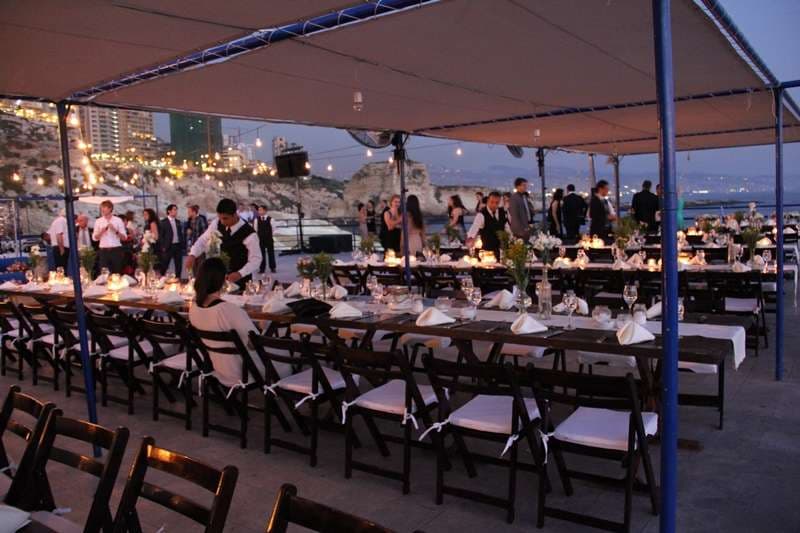 An outdoor banquet under canopy with the coastline at dusk at Sporting Club Beach