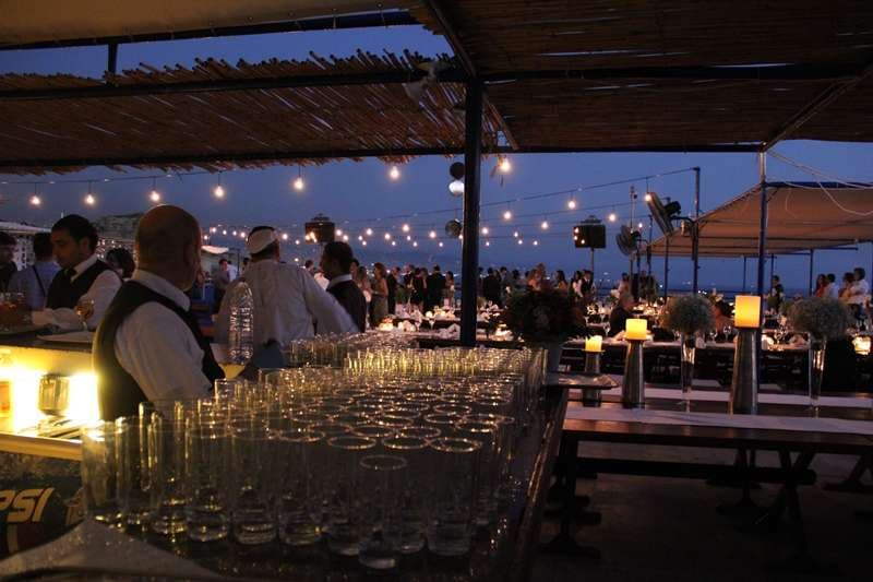 A seafront event bar set with rows of glasses at dusk at Sporting Club Beach