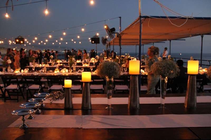 An outdoor evening banquet with candles and floral centrepieces at Sporting Club Beach