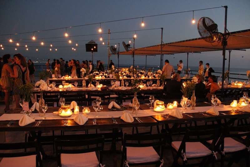 Outdoor banquet tables set with candles at dusk at Sporting Club Beach, Ras Beirut