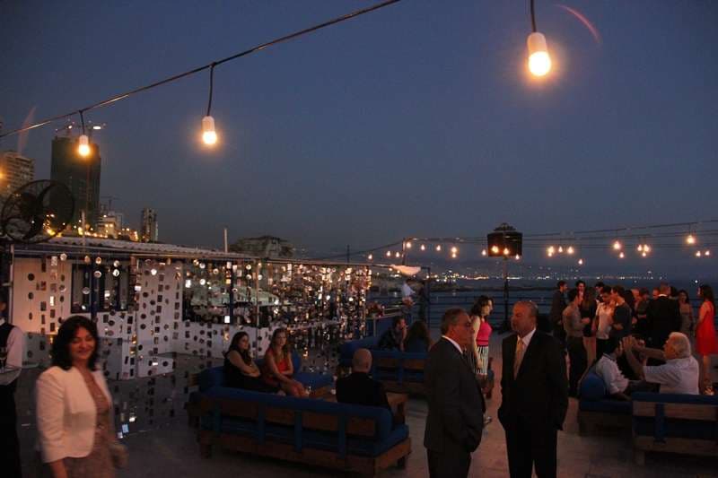 An evening terrace gathering on lounge sofas under string lights at Sporting Club Beach