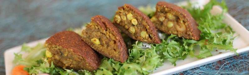 Kibbeh plated over greens at Sporting Club Beach