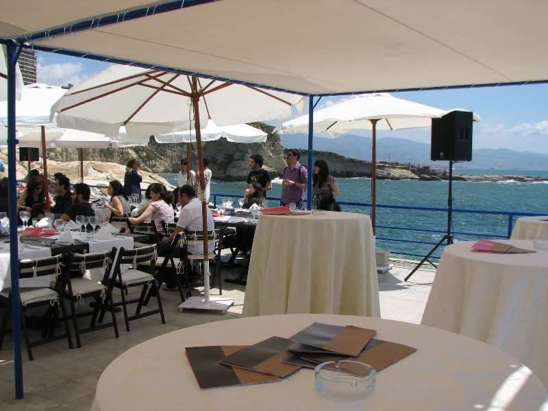 An outdoor seaside event under umbrellas with guests at Sporting Club Beach, Ras Beirut