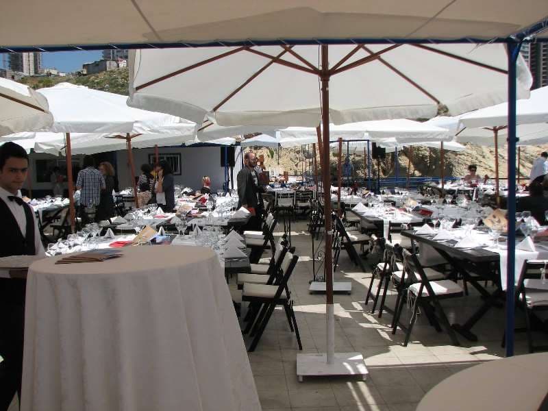 An outdoor daytime event under umbrellas with a buffet and guests at Sporting Club Beach
