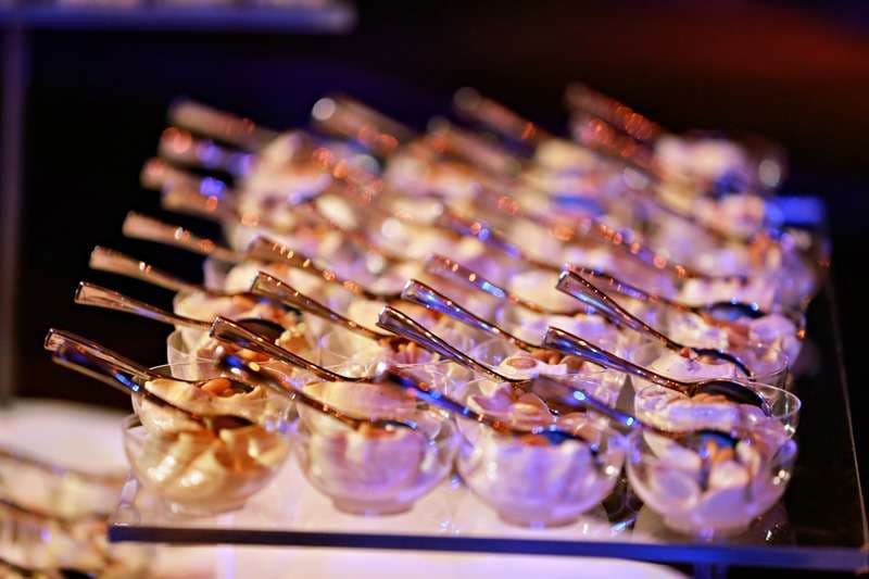 Small bites on spoons arranged in glass bowls for service at Sporting Club Beach