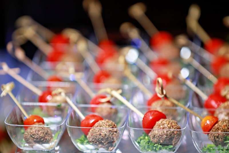 Crusted meatballs with cherry tomatoes on picks in small cups at Sporting Club Beach