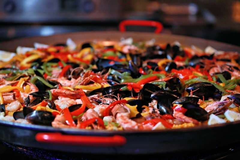 A seafood paella with shrimp, mussels and peppers in a large pan at Sporting Club Beach