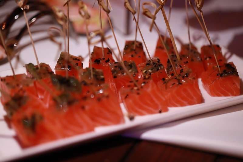 Salmon cubes with black sesame on picks, arranged on a plate, at Sporting Club Beach