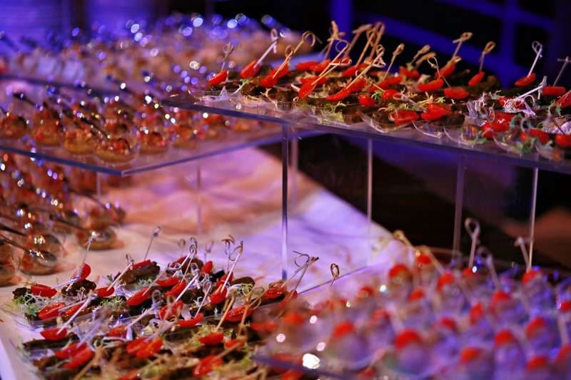Canapés with cocktail picks on small plates, tiered for service, at Sporting Club Beach