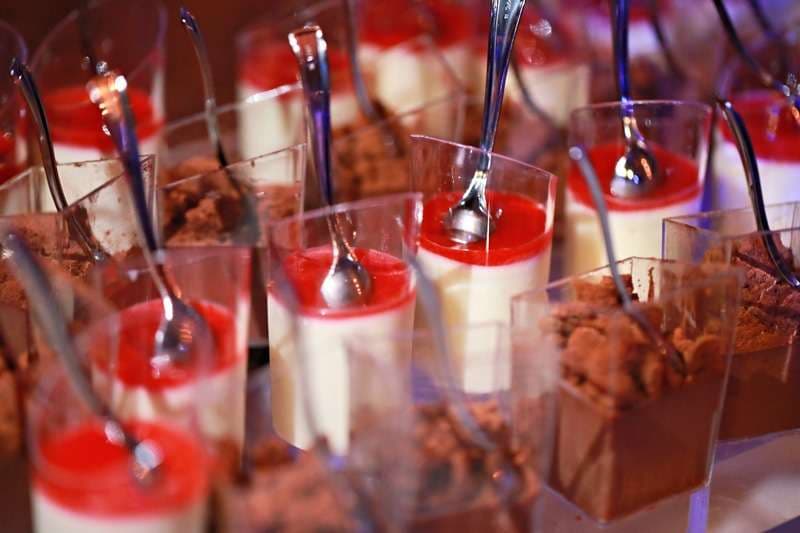Dessert cups of panna cotta with crumble, with spoons, at Sporting Club Beach