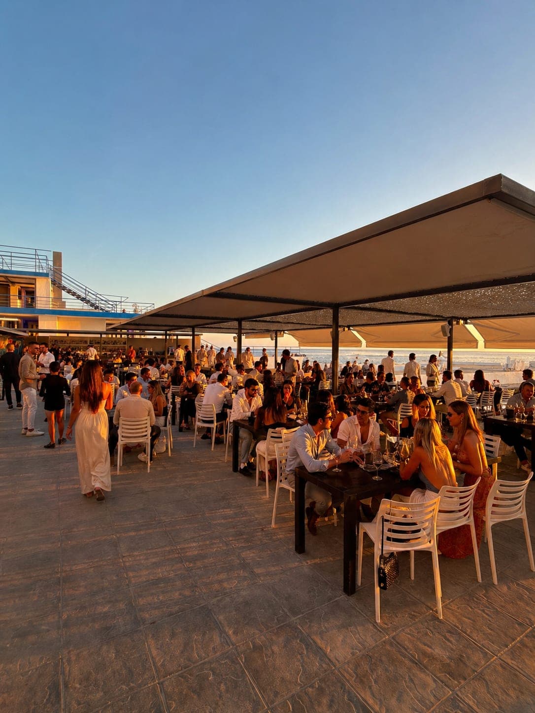 Guests on the Sunset Bar terrace at golden hour, Sporting Club Beach